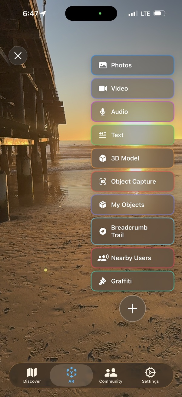 Screenshot of the AR content menu showing Photos, Video, Audio, Text, 3D Model, Object Capture, Breadcrumb Trail, Nearby Users and Graffiti options over a beach sunset