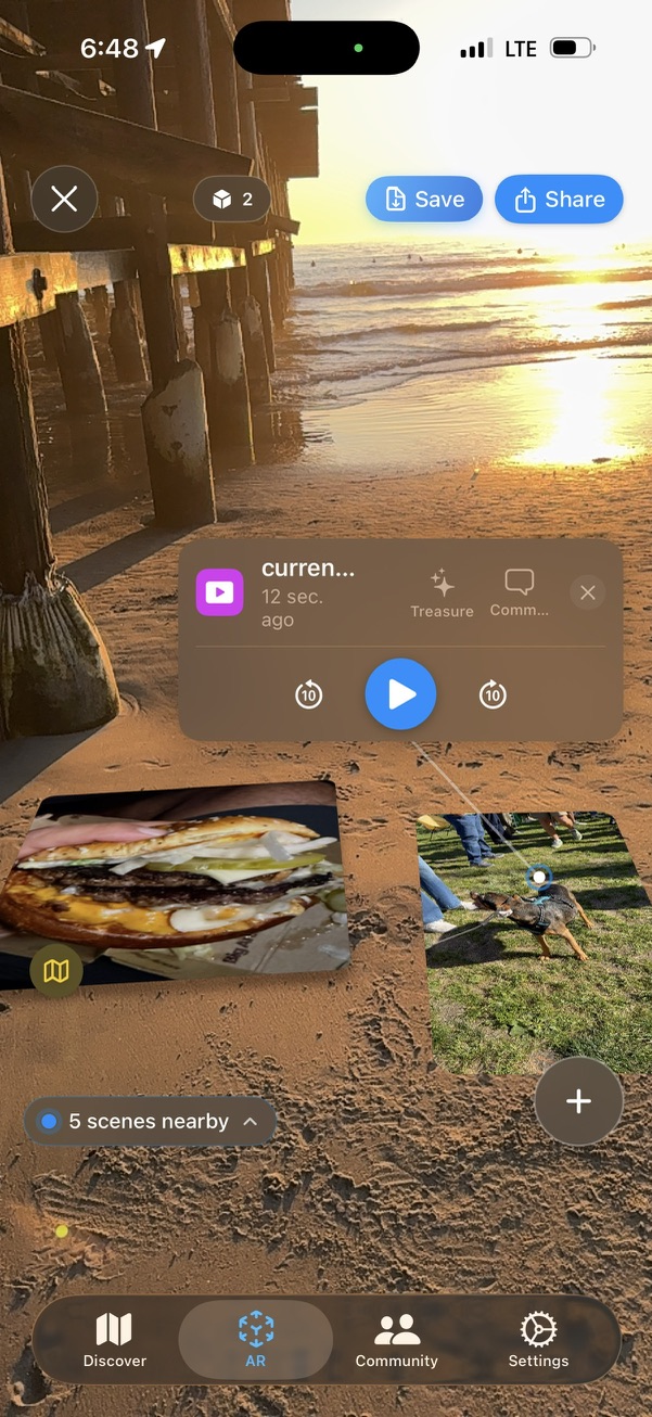 Screenshot of an AR scene at the beach showing a video, a photo of a burger, and a photo of a dog placed in mid-air